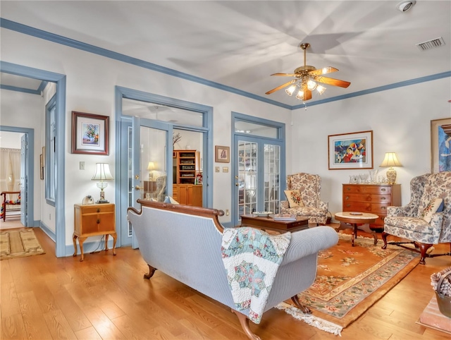 living room featuring french doors, crown molding, ceiling fan, and light hardwood / wood-style flooring