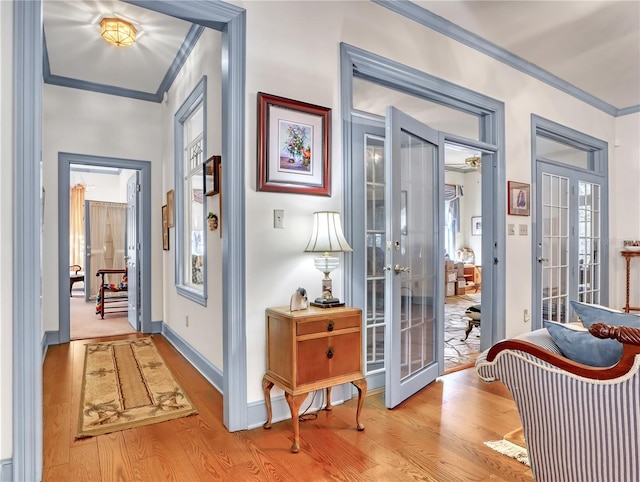 interior space with french doors, ornamental molding, and light wood-type flooring