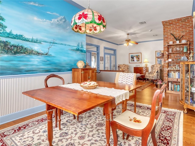 dining area with brick wall, ceiling fan, and light wood-type flooring