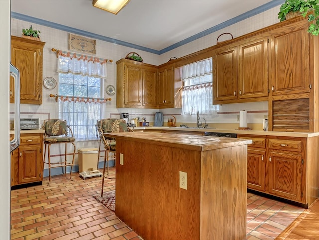 kitchen with ornamental molding, a kitchen island, sink, and a wealth of natural light