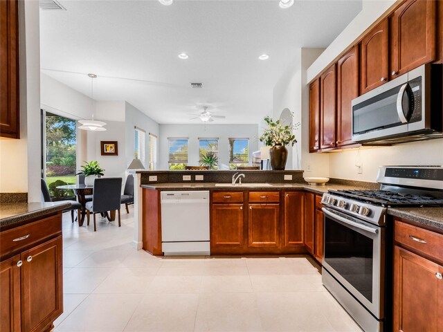 kitchen with appliances with stainless steel finishes, ceiling fan, light tile flooring, decorative light fixtures, and kitchen peninsula