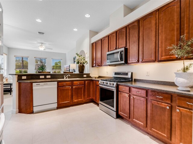 kitchen with kitchen peninsula, appliances with stainless steel finishes, sink, light tile floors, and ceiling fan