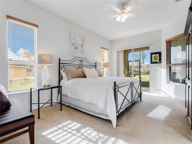 bedroom featuring light colored carpet, ceiling fan, access to exterior, and multiple windows