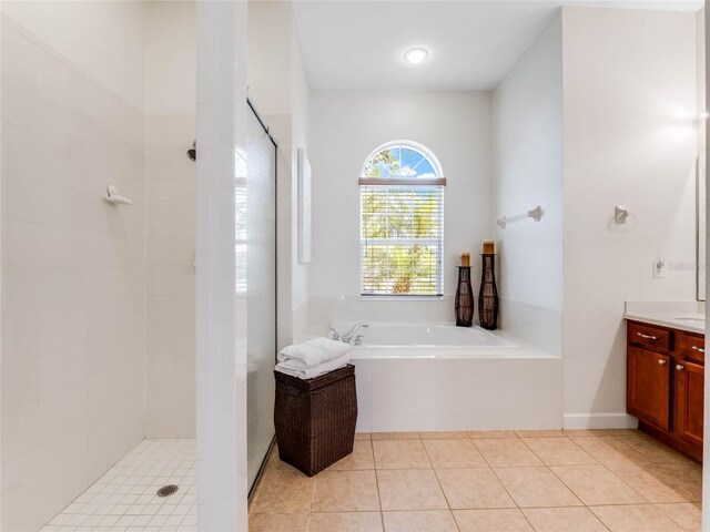 bathroom featuring tile floors, vanity, and plus walk in shower