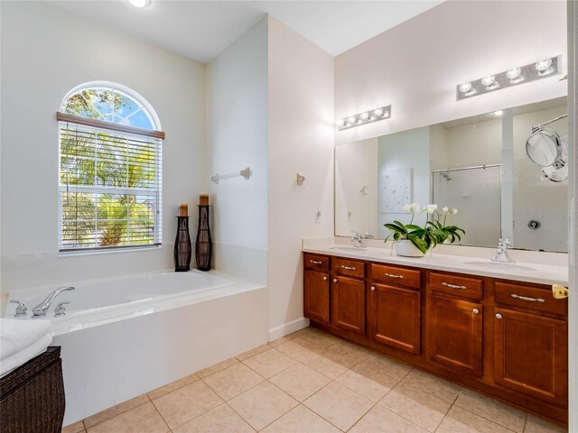 bathroom featuring tiled tub, dual vanity, and tile flooring