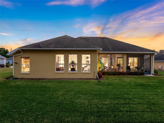 back house at dusk with a lawn