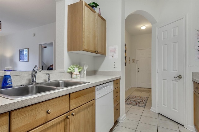 kitchen with light tile floors, light brown cabinetry, dishwasher, and sink