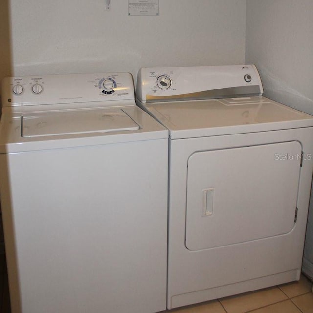 laundry room featuring washer and clothes dryer and light tile flooring