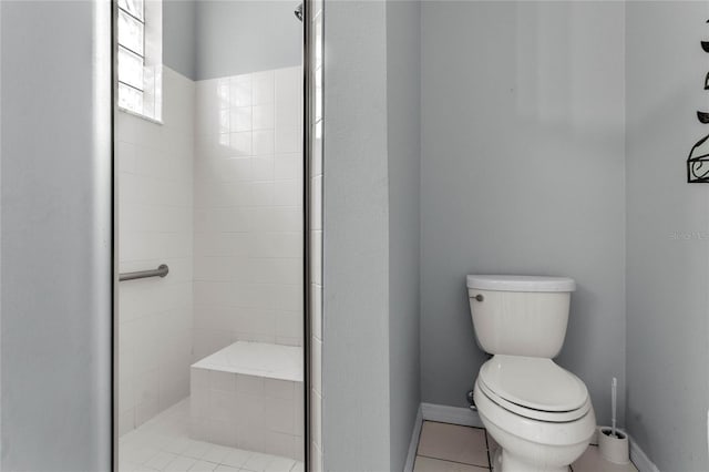 bathroom with a tile shower, tile patterned flooring, and toilet