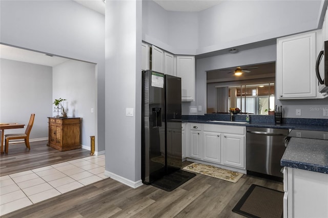 kitchen featuring stainless steel dishwasher, ceiling fan, a high ceiling, light hardwood / wood-style floors, and white cabinetry