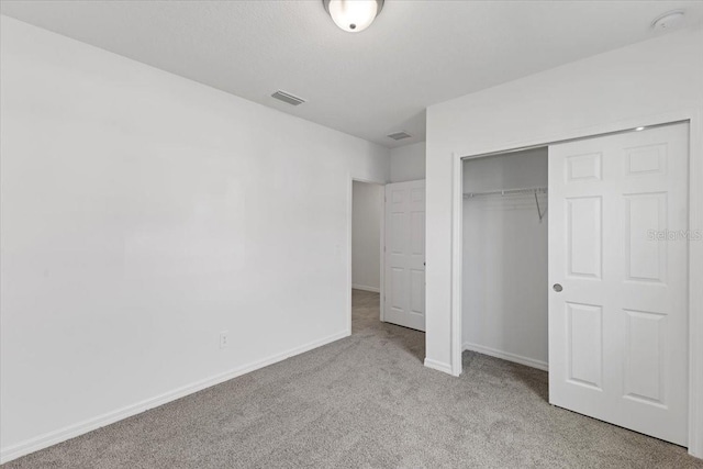 unfurnished bedroom with light colored carpet and a closet