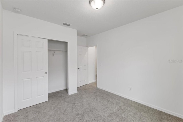 unfurnished bedroom with light carpet and a closet