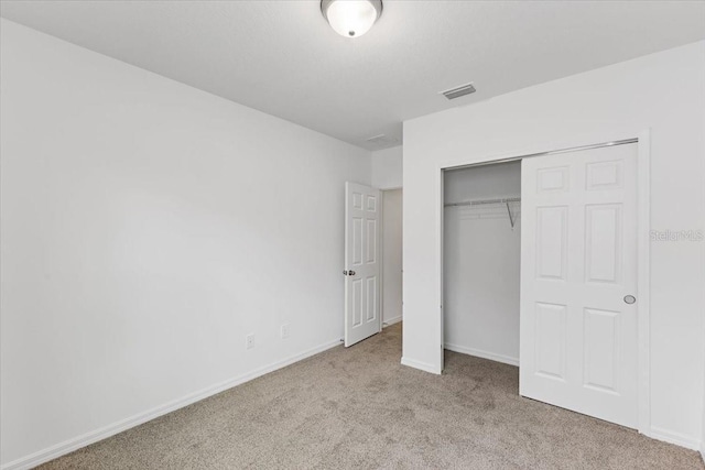 unfurnished bedroom featuring light carpet and a closet