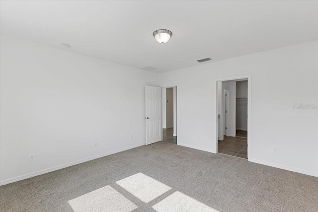 unfurnished bedroom with carpet floors, a spacious closet, and a closet