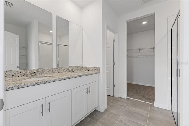 bathroom featuring tile patterned flooring, vanity, and a shower with door