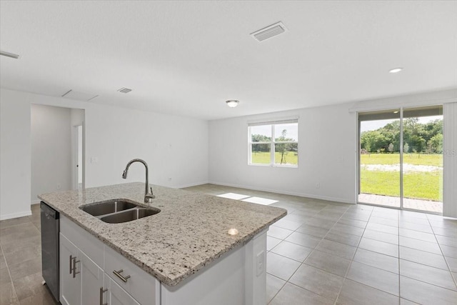 kitchen with white cabinets, a center island with sink, light stone countertops, and sink