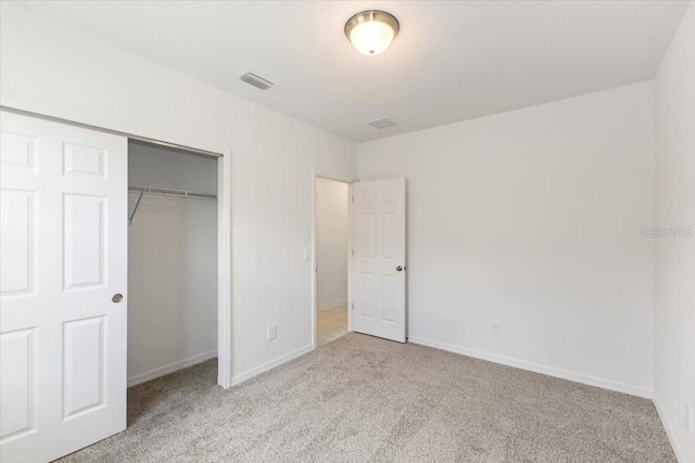 unfurnished bedroom with light colored carpet and a closet