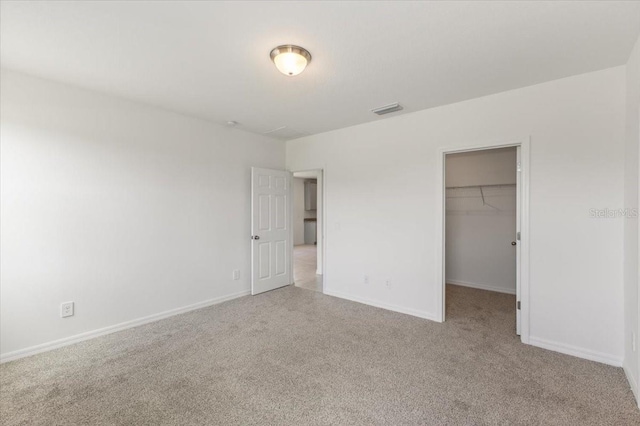 unfurnished bedroom with a walk in closet, carpet flooring, and a closet