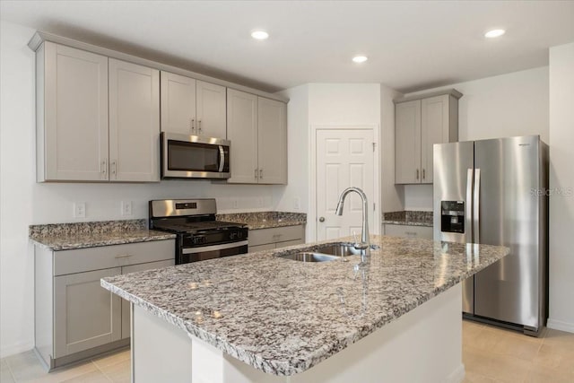 kitchen featuring appliances with stainless steel finishes, gray cabinets, sink, and a kitchen island with sink