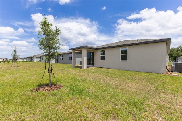 back of house featuring a lawn and central air condition unit