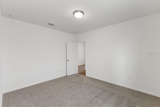 carpeted empty room featuring a textured ceiling