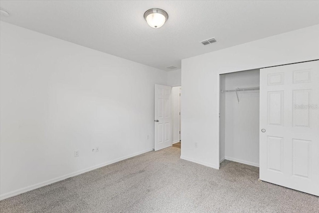 unfurnished bedroom featuring a closet, light carpet, and a textured ceiling