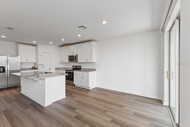 kitchen featuring appliances with stainless steel finishes, sink, a center island with sink, and white cabinets