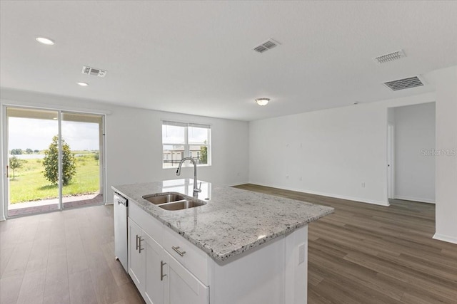 kitchen featuring dishwasher, sink, white cabinets, a kitchen island with sink, and light stone countertops