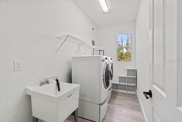 washroom featuring independent washer and dryer, light hardwood / wood-style flooring, and sink