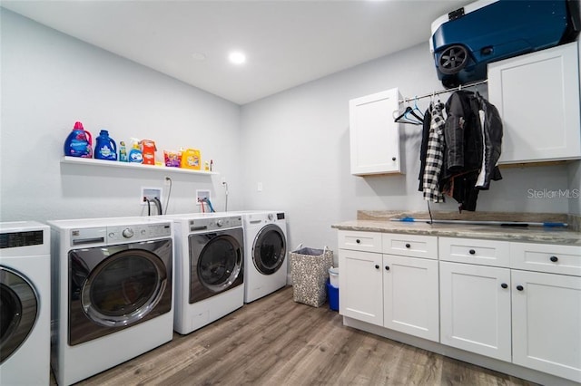 laundry area featuring cabinets, washer and clothes dryer, and light hardwood / wood-style floors