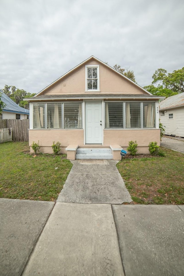 bungalow-style home with a front lawn and a sunroom