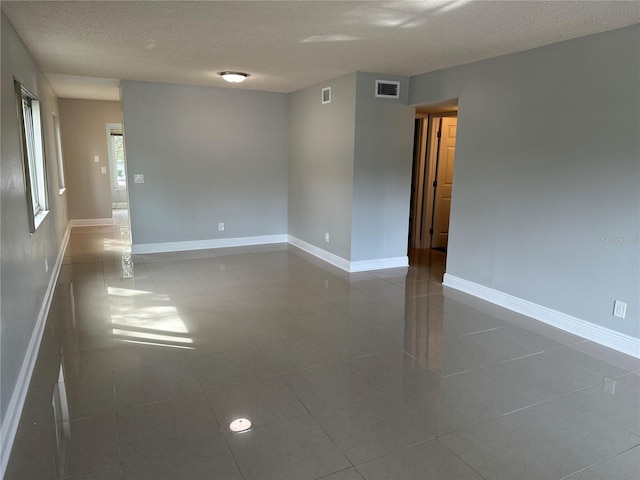 empty room with a textured ceiling and tile patterned flooring