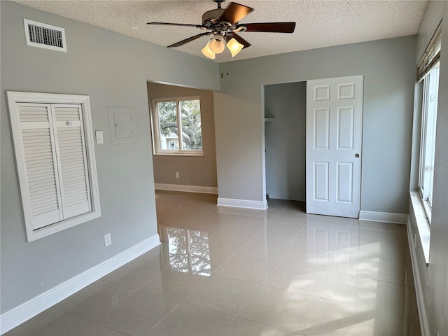 tiled spare room with a textured ceiling, electric panel, and ceiling fan