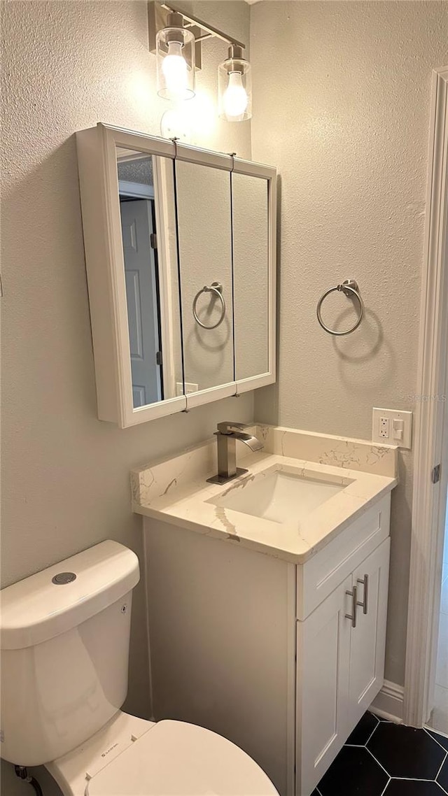 bathroom with toilet, vanity, and tile patterned flooring