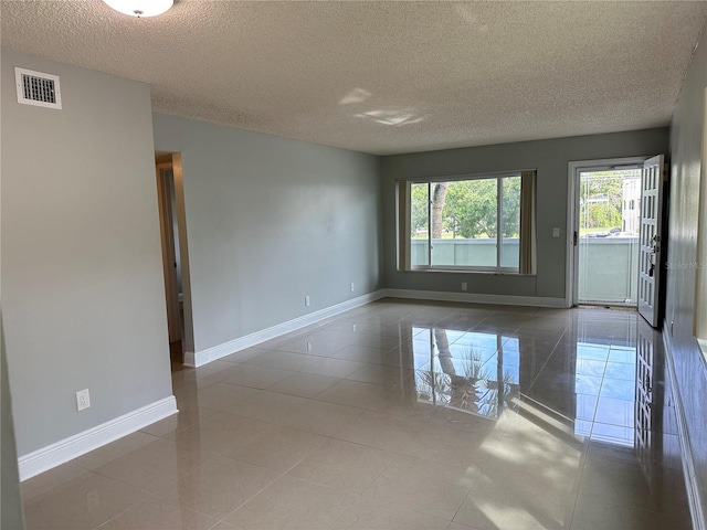 tiled empty room with a textured ceiling