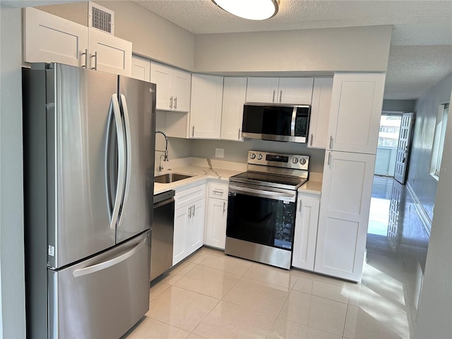 kitchen with sink, white cabinets, stainless steel appliances, and a textured ceiling