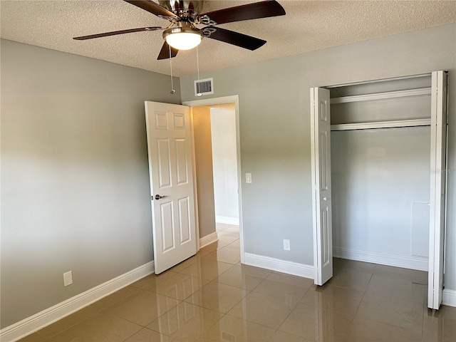 unfurnished bedroom with tile patterned flooring, a textured ceiling, a closet, and ceiling fan