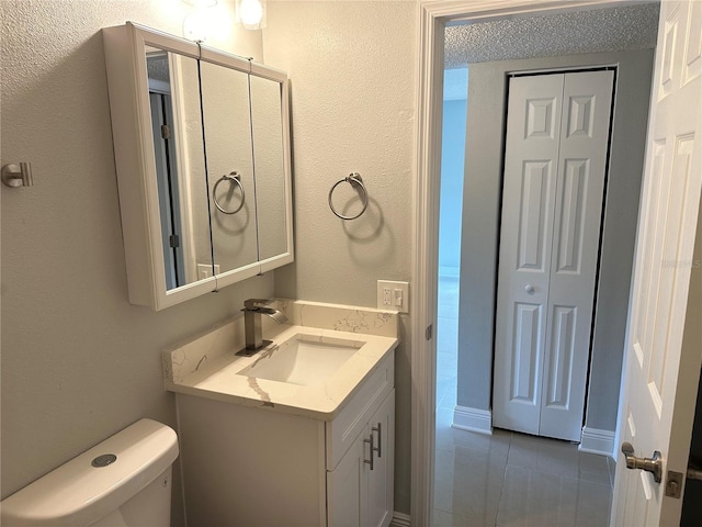 bathroom with toilet, vanity, and tile patterned flooring