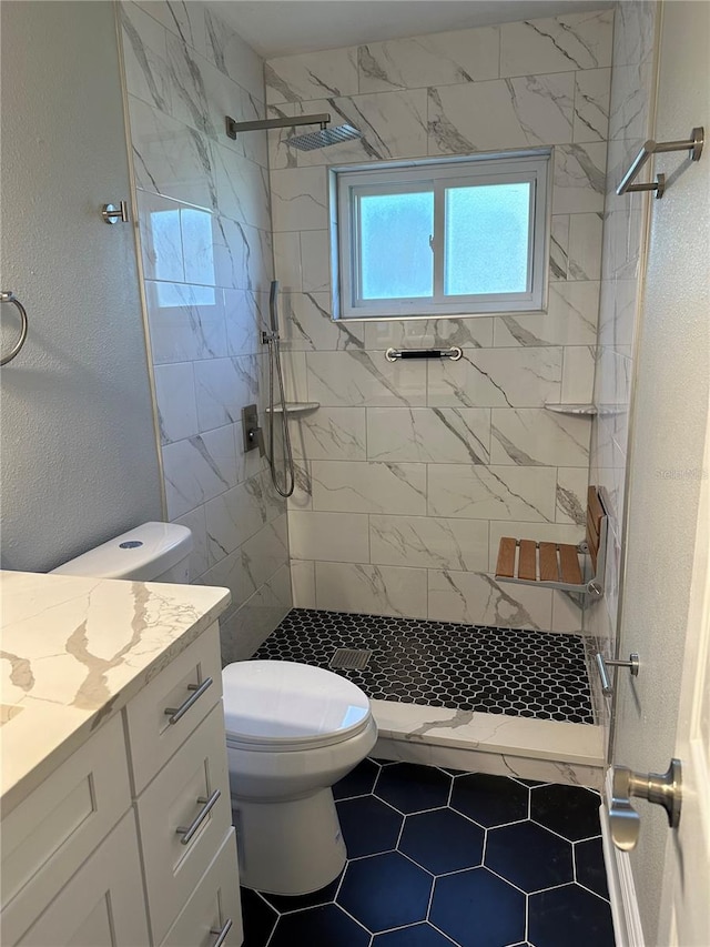 bathroom featuring vanity, tiled shower, toilet, and tile patterned floors