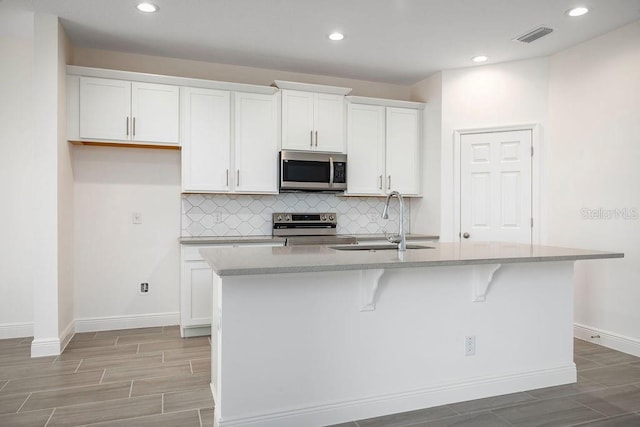 kitchen featuring white cabinetry, a center island with sink, appliances with stainless steel finishes, and sink