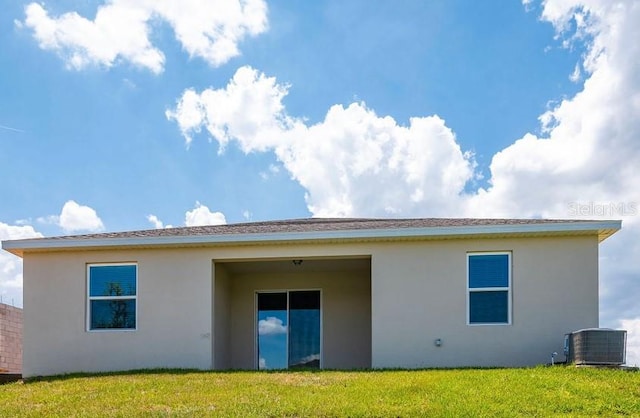 back of property featuring central AC unit and a lawn