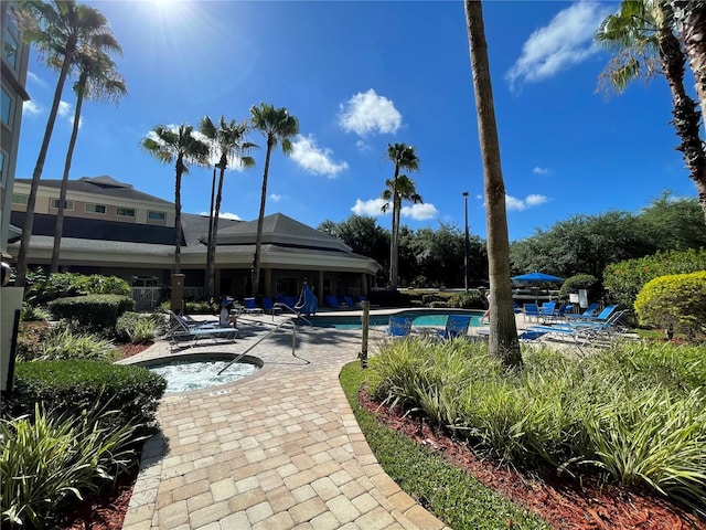 view of community with a patio area and a swimming pool with hot tub