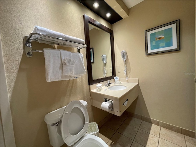 bathroom with toilet, sink, and tile patterned flooring