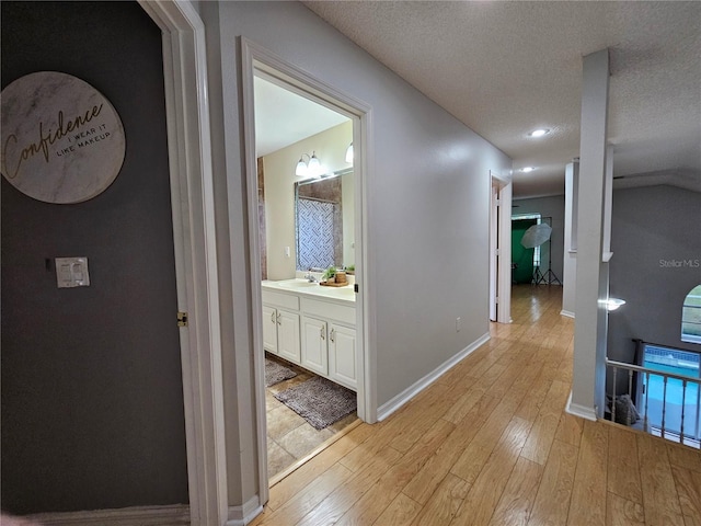 hall featuring light hardwood / wood-style flooring, a textured ceiling, and sink