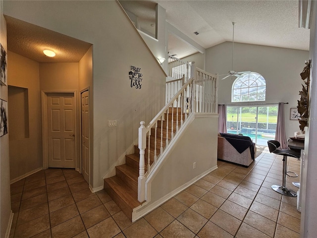 staircase with ceiling fan, tile patterned floors, high vaulted ceiling, and a textured ceiling