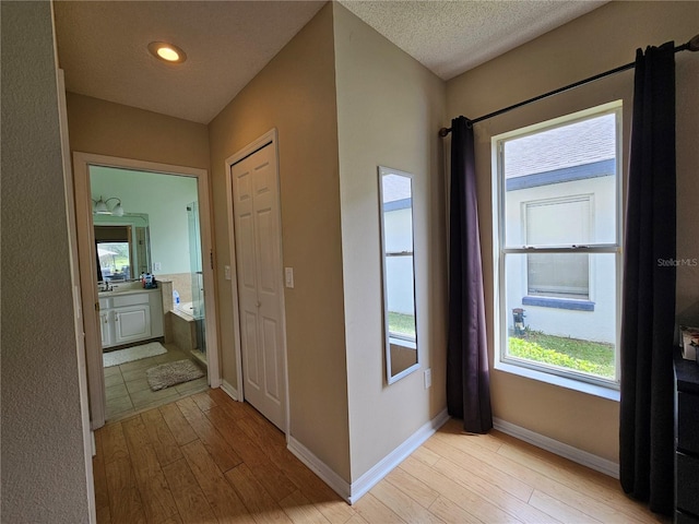 hall with a textured ceiling and light hardwood / wood-style flooring