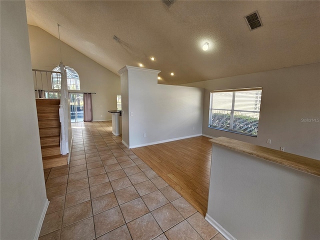 interior space with high vaulted ceiling, a textured ceiling, and light tile patterned flooring