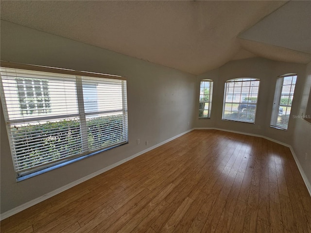 unfurnished room with hardwood / wood-style flooring and lofted ceiling