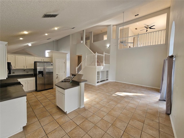 kitchen featuring backsplash, sink, high vaulted ceiling, stainless steel fridge with ice dispenser, and white cabinetry