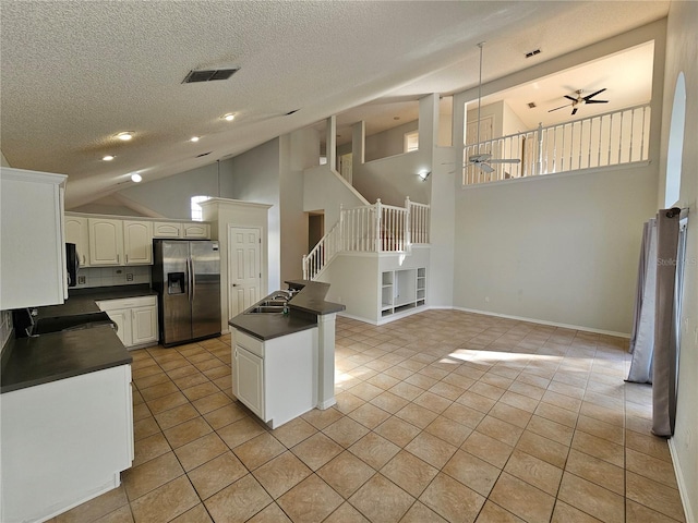 kitchen featuring white cabinets, ceiling fan, kitchen peninsula, stainless steel refrigerator with ice dispenser, and a textured ceiling